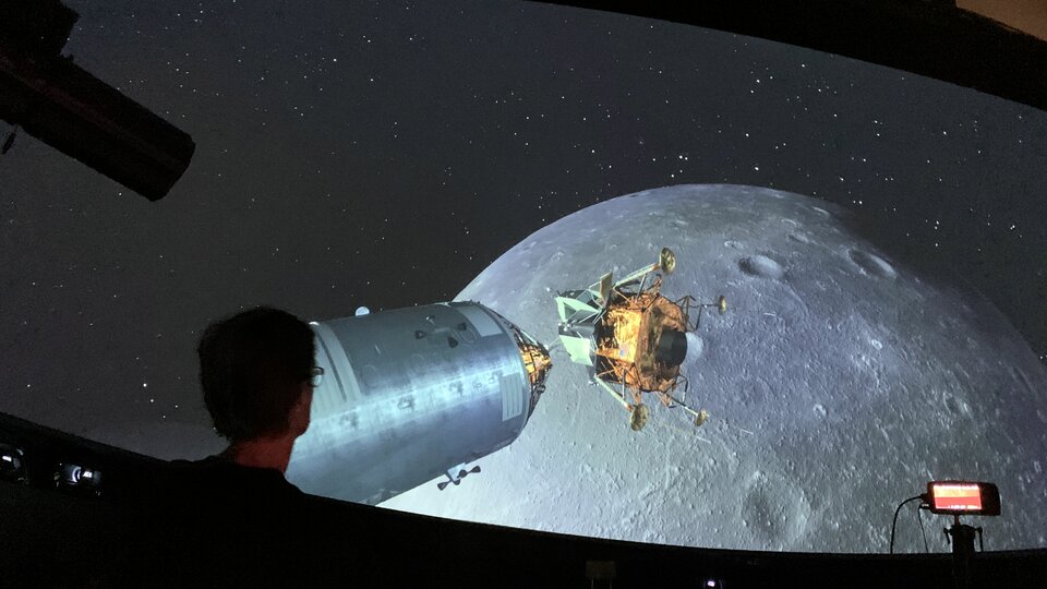 Besucher im Space Eye bei einer Planetariumsshow, die den Anflug des Mondes zeigt.