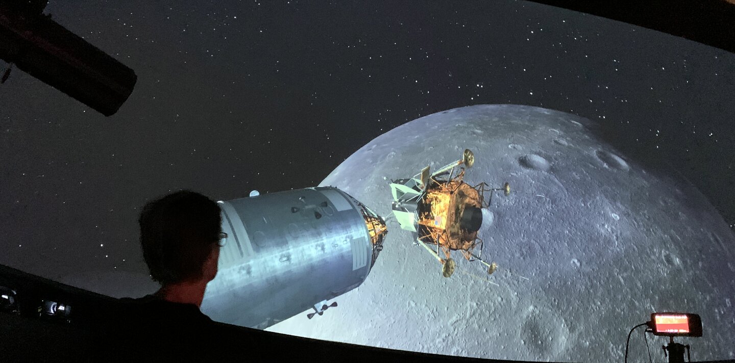 Besucher im Space Eye bei einer Planetariumsshow, die den Anflug des Mondes zeigt.
